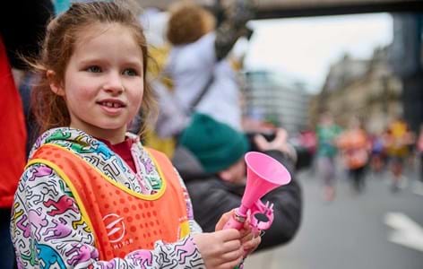 child at side of marathon route in Place2Be vest holding mini pink megaphone