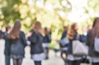 An out of focus image of secondary school students gathered on school grounds.