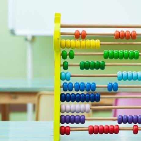 colourful abacus on classroom desk in front of whiteboard