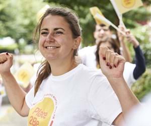 Place2Be supporter holding hands in the air cheering and people waving flags