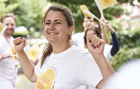Place2Be supporter holding hands in the air cheering and people waving flags