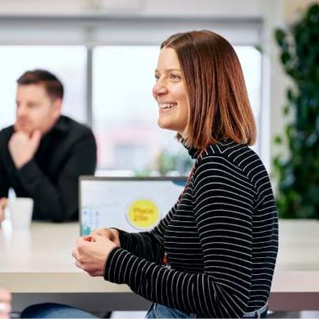 two people sitting at desk with laptop and coffee mugs