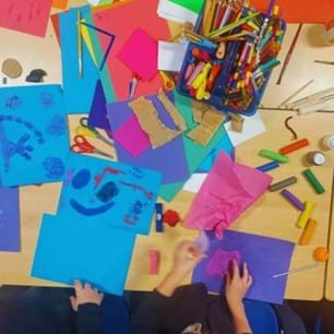 bird's-eye view of classroom table covered in colourful arts supplies