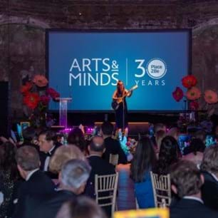 Katie Melua standing on stage with guitar in front of tables with gala guests
