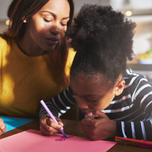 Child drawing with mum by her side