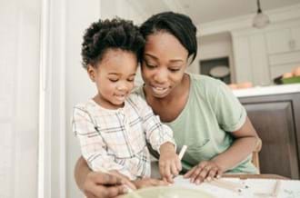 A woman and a young child drawing and smiling together