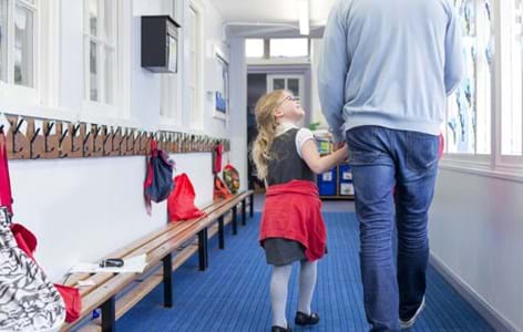 Little girl walking through her nursery corridor with her father. She is holding his hand and looking up to him with a smile on her face.