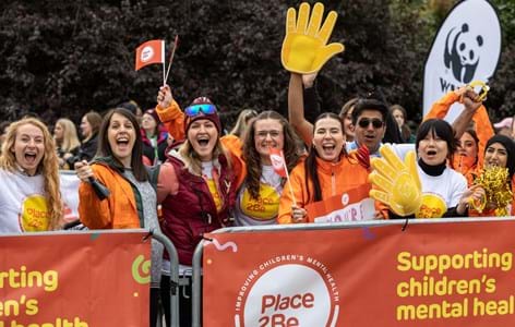 A Place2Be counsellor sitting with a group of primary-aged school pupils, who are doing a group activity