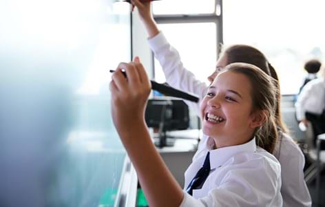 Girl writing on school whiteboard and smiling